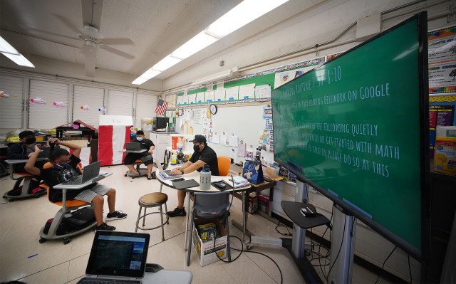 Honowai Elementary School 4th grade teacher Dalen Izumo with large monitor and students using laptop computers.