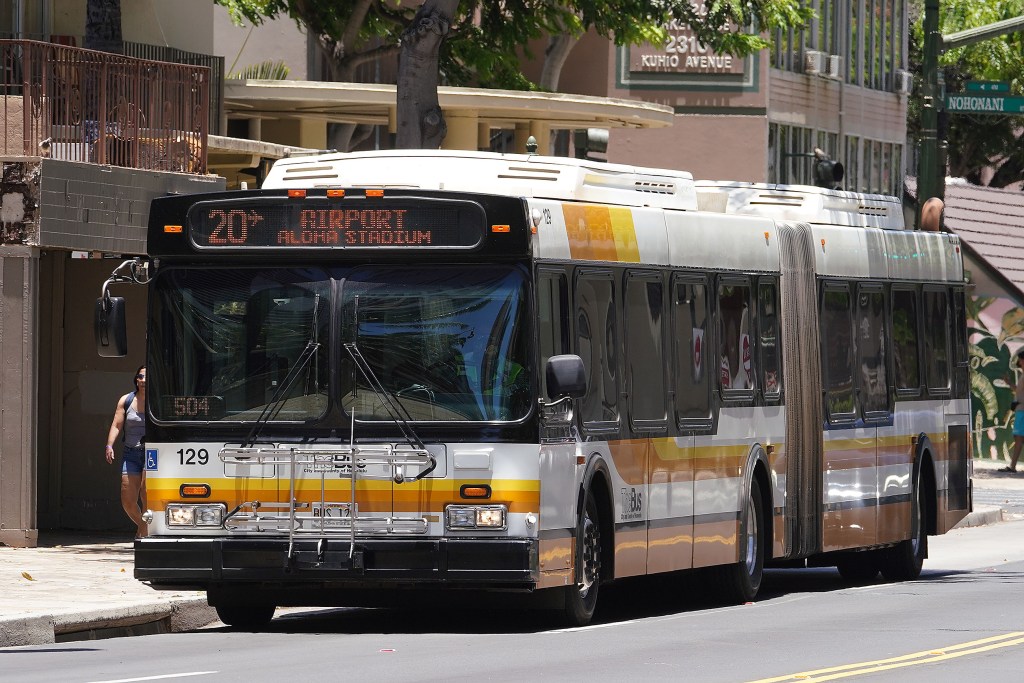 TheBus Route 20 rolls along Kuhio Avenue on its way to the airport. Passengers along the route readied their luggage ready to board the bus to the airport.
