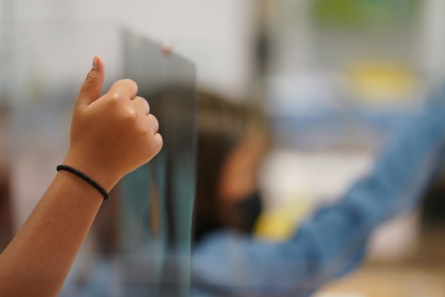 Holomua Elementary School 4th grade students raise their thumbs in Mr. Suan's classroom.