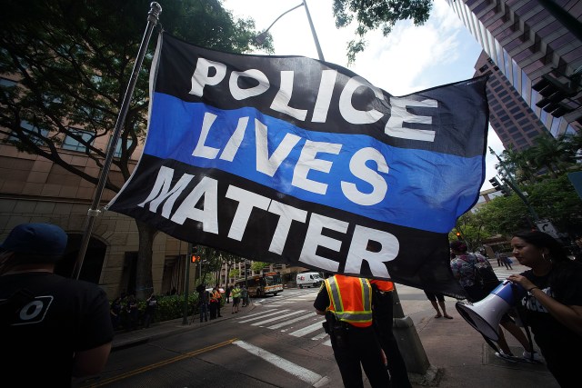 An HPD supporter holds a large flag that reads, “Police Lives Matter’ fronting DIstrict Court.