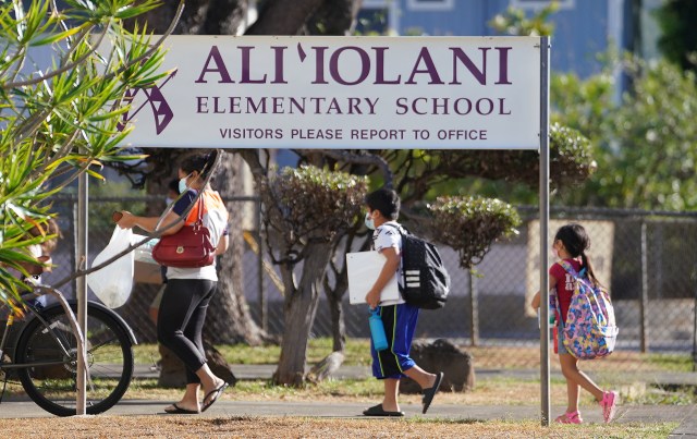 Aliiolani Elementary School students walk carrying all their school supplies on the first day of school.