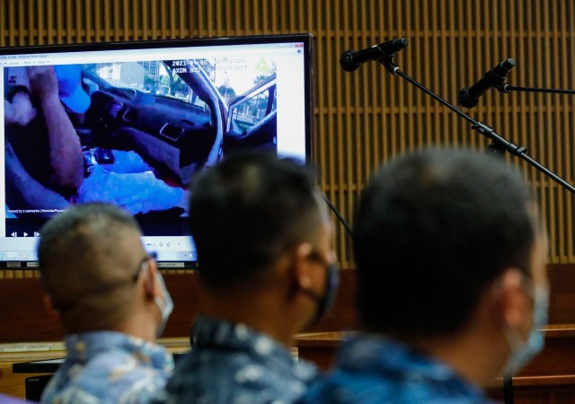 Honolulu police officers Geoffrey Thom, left, Christopher Fredaluces, and Zackary Ah Nee look at body camera footage on the monitor screen in the district courtroom of Judge William M. Domingo during preliminary hearings for three Honolulu police officers in the killing of Iremamber Sykap on Tuesday, Aug. 17, 2021, in Honolulu. (POOL PHOTO/Jamm Aquino/Honolulu Star-Advertiser).