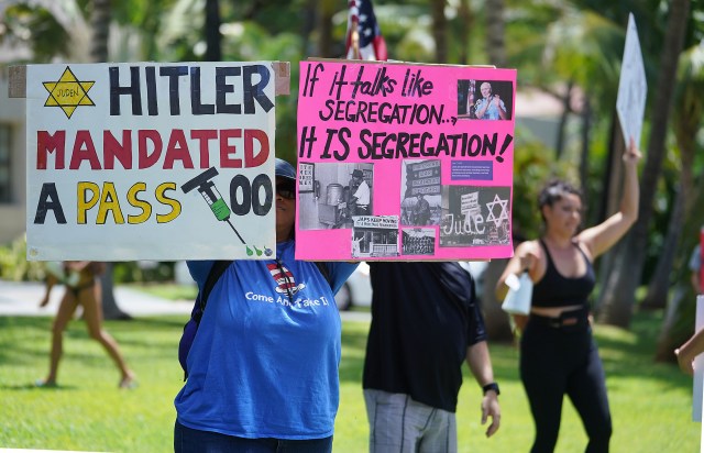Anti Covid-19 Vaccination demonstrator holds a sign with a reference to Hitler while demonstrating outside Honolulu Hale.