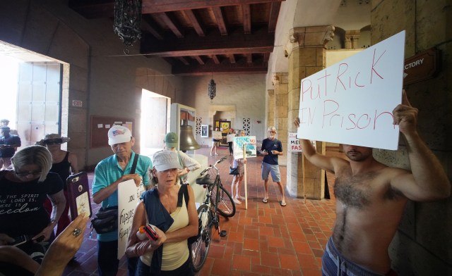 Demonstrator holds a sign ‘Put Rick in Prison’ inside Honolulu Hale. Honolulu Police officers were on the scene during a council meeting.
