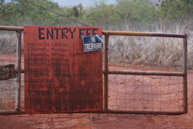 Interesting sign outlining prices for getting thru gate. $100,000 for looking inside on a gate in the DHHL Hawaiian homestead properties near the Molokai Airport.