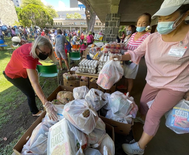 Hee Jong Chun, right, and other volunteers handing out bags of food as a part of the Serving Aloha event at Central Union Church. They serve over 450 people per week with food donated from the Hawaii Food Bank to help fight against food insecurity here on the island.(Photo: Ronen Zilberman/Civil Beat)