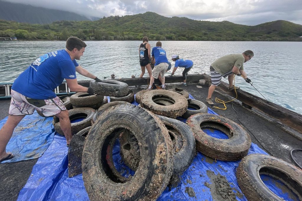 Volunteers for the Ocean Defenders Alliance (ODA) pull tires up out of the water after being removed from the ocean floor by divers Sunday, September 12, 2021. This event marked the first time anyone had organized efforts to remove debris from the bay. (Ronen Zilberman photo Civil Beat)