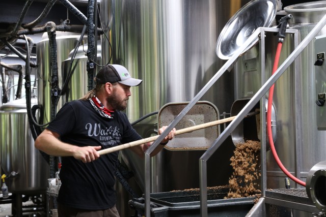 Brewer Jake Robertson uses a large paddle to take grains outside the mashtun vessel at the Waikiki Brewing Company.