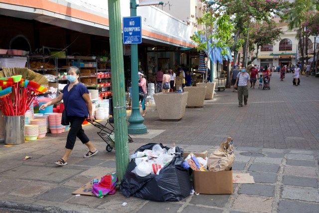 A pile of trash sits near a crosswalk and near a "no dumping" sign in Chinatown.