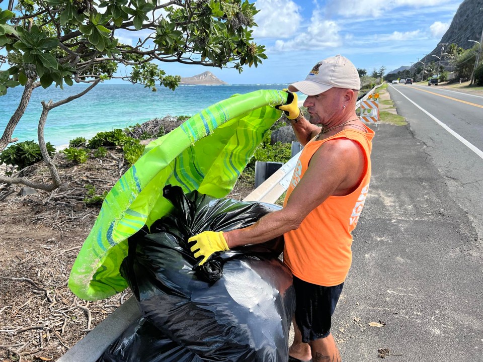 Lokelo Schmid, a volunteer with 808-Cleanups collects trash from the beach along the Kalanianaole Hwy, in Waimanalo Bay during a beach clean-up on Sunday, November 21, 2021.  (Ronen Zilberman photo Civil Beat)