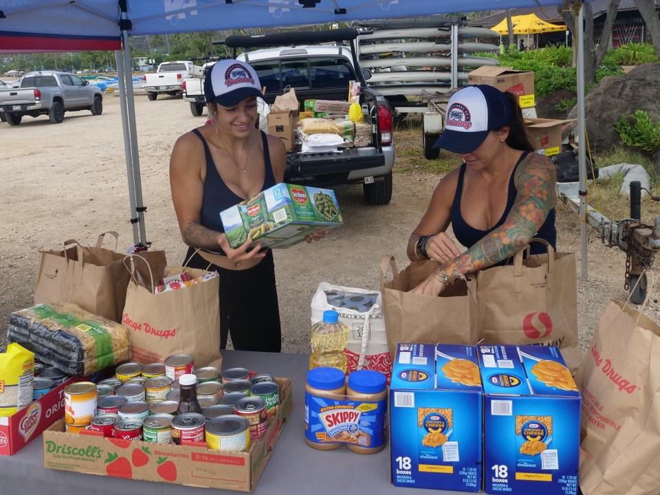 Volunteers Cassandra Padilla (left) and Heidi Strauss organize food donations during the Hui Nalu O' Canoe Club food drive in Hawaii Kai, Saturday, November 13, 2021. Food items collected during the drive will be donated to those in need in the Waimanalo community. (Ronen Zilberman photo Civil Beat)