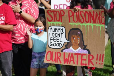 Demonstrators hold signs during a protest against the recent US Navy fuel spill while standing fronting the Federal Building.