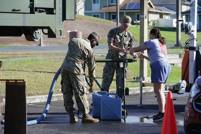 Navy personnel assist residents with filling containers at Halsey Terrace Community Center.