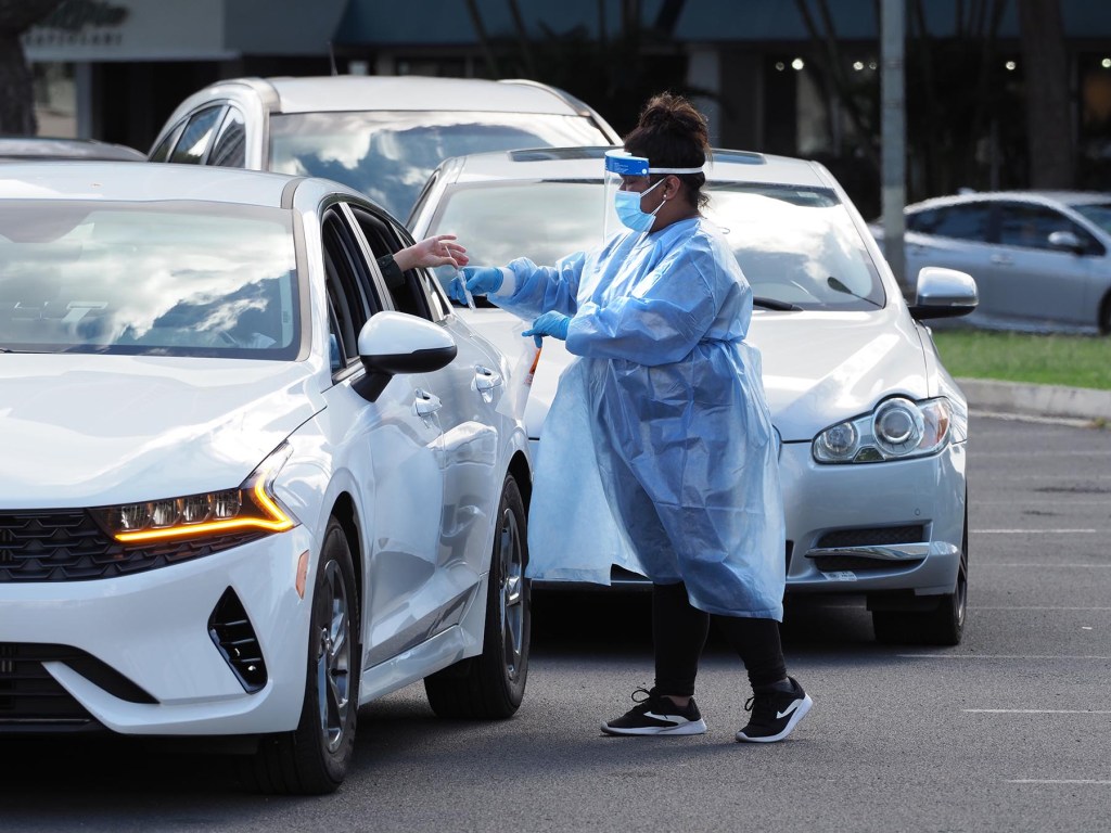A medical technician collects COVID-19 nose swab samples from people lined up in their cars, around the block, at the Blaisdell drive-through testing site in Honolulu, Monday, December 27, 2021. (Ronen Zilberman photo Civil Beat)