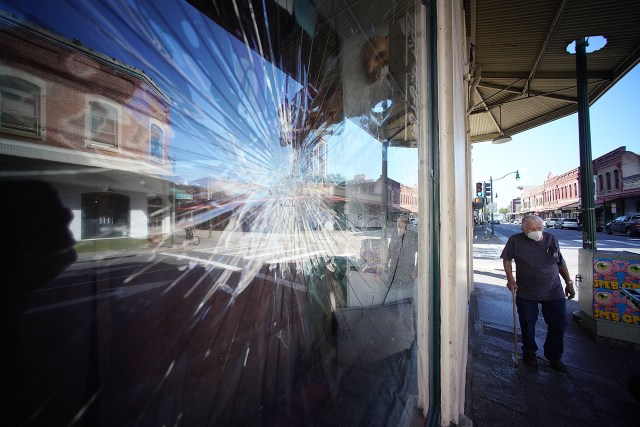 Reflection of Nuuanu Avenue with Black Cat Tattoo's shattered large glass window in foregound.