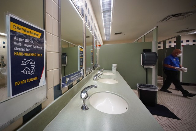 NEX mens restroom sign says water source cleared for handwashing only. 'Do not consume'.