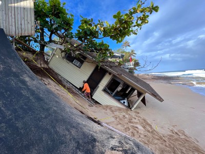 At Rocky Point, on Oahu's North Shore, Hugo Villalobos walks up the sandy bluff alongside house after it collapsed and slid onto the beach below the night before,Tuesday, March 1, 2022. Villalobos said he lived in the house for nearly 30 years. (Ronen Zilberman photo Civil Beat)
