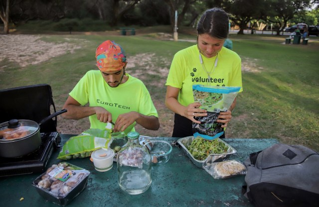 A photograph of Liz Woodall and Rashawn Hunter cooking dinner at a picnic table at Kanaha Beach Park
