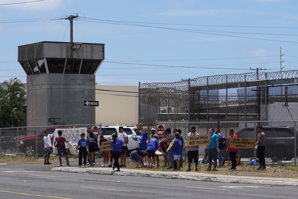 Demonstrators hold signs fronting the OCCC Oahu Community Correctional Center.