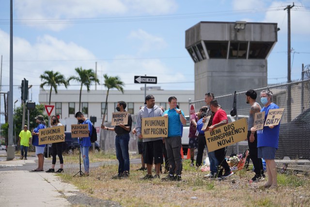 Demonstrators hold signs fronting the OCCC Oahu Community Correctional Center.