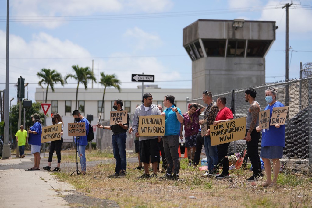 Demonstrators hold signs fronting the OCCC Oahu Community Correctional Center.