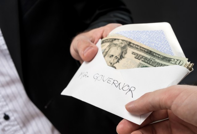 Man giving an envelope full of cash with the word governor written in it