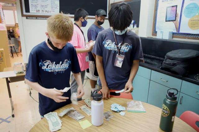 A photo of students counting earnings from Lokelani Intermediate School's student-run store.