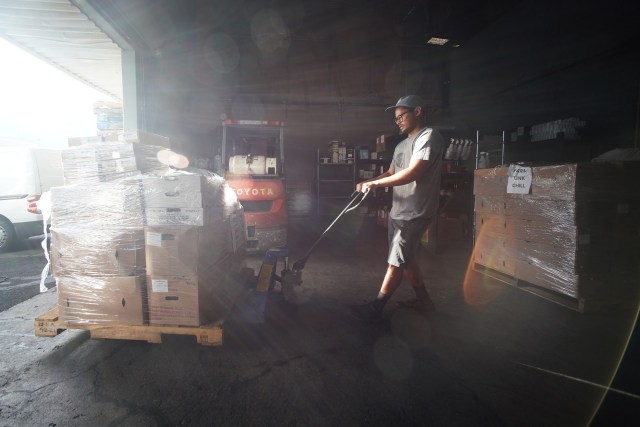 Farm Link Hawaii delivery person, Jimi Cortez unloads an early morning pickup of interisland farmed vegetables and more, offloading at the Farm Link Hawaii warehouse.