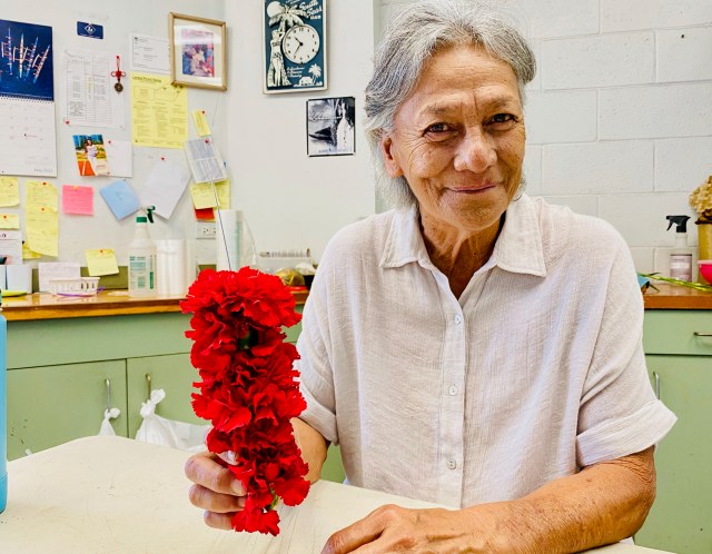 Kuulei Kaʻae stringing a double red carnation lei at Pua Melia Lei Stand at the Daniel K. Inouye International Airport.