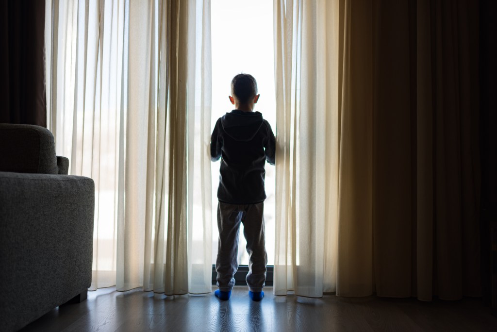 Boy from back, looking trough the window.