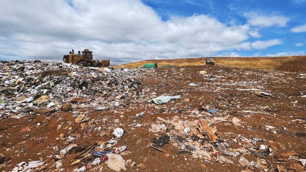 A bulldozer moves trash into mounds