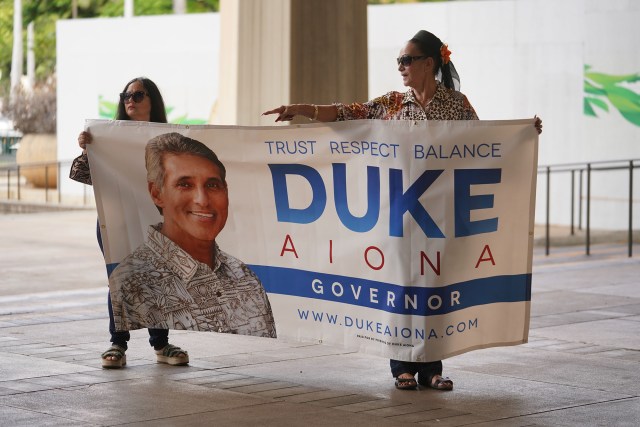 Supporters move a Duke Aiona banner before the start of the press conference at the Capitol Rotunda.