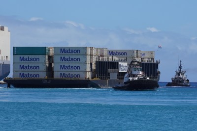 Matson container barge is pulled out to sea from Honolulu Harbor. The tugboat at right was assisting the barge make the turn and is heading back.