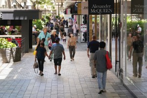 Masked and unmasked people walk along the shops at Ala Moana Shopping Center.
