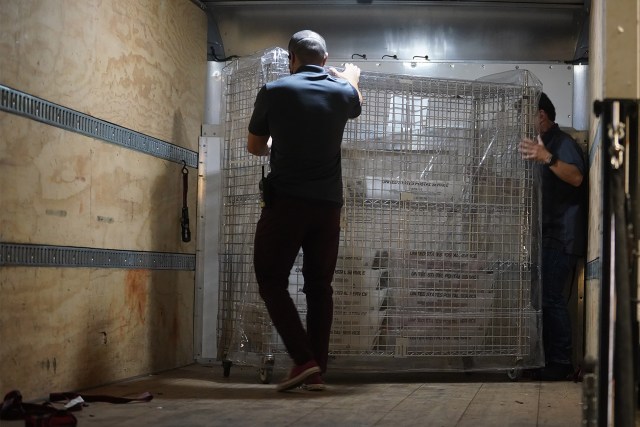 2022 primary election staff move ballots in sealed rolling caged storage containers to be sorted then counted at the Capitol.