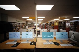 McKinley High School's Daniel Inouye Library located on the second floor of this building.. A view of computers in foreground with many rows of books.