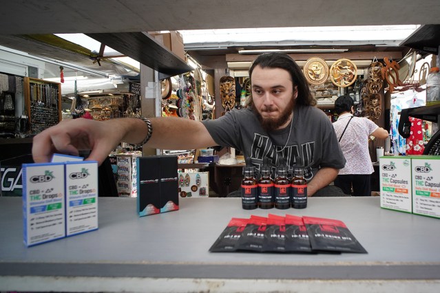 Pinky's Hempire sales employee Kash Lopez sits in the kiosk located at Duke's Lane in Waikiki.