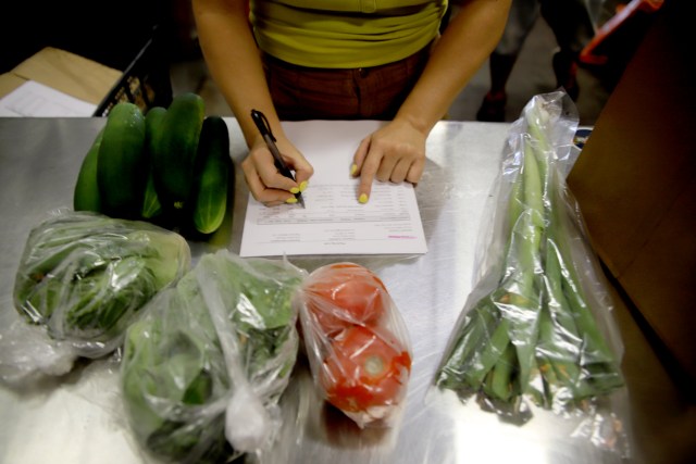 A photograph of a Maui Food Hub worker putting together weekly produce bags