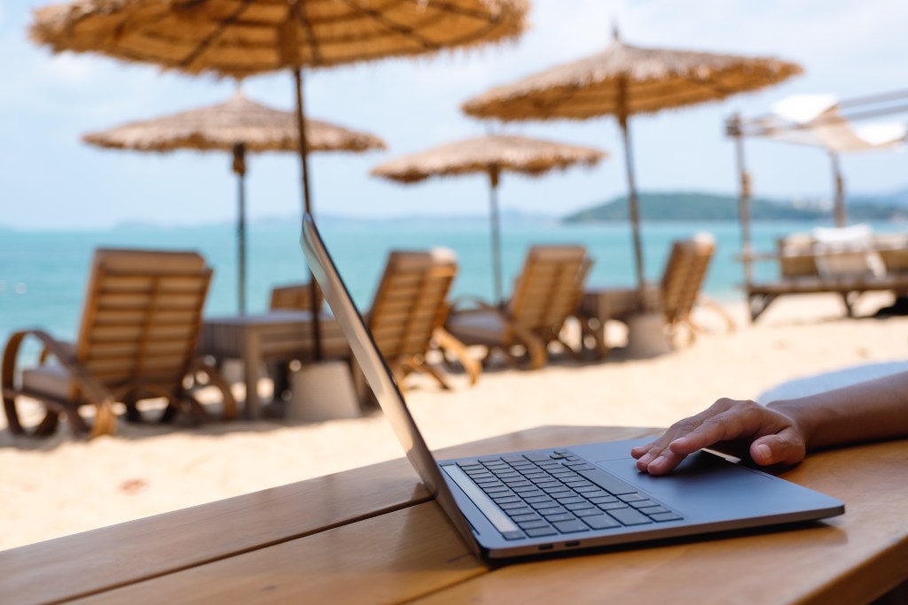 Closeup of a woman working and touching on laptop touchpad on the beach