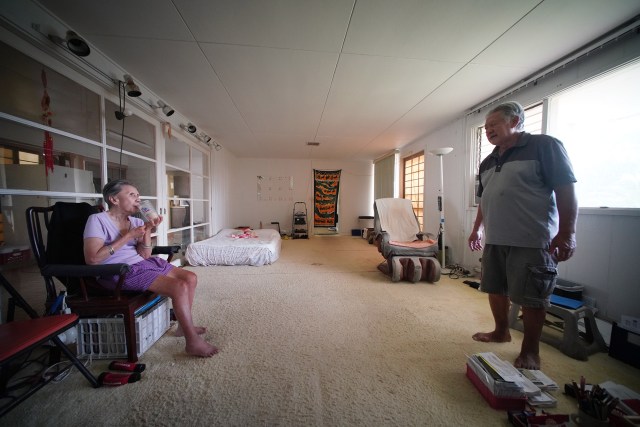 Homeowner Clayton Chang helps his wife Maureen Chang with breakfast in their living space/living room. Chang has cleared out most of his rooms after a major flood damaged his home. Chang has been waiting years to get a DPP permit to demolish and rebuild.