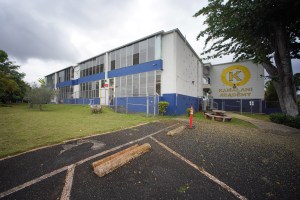 The Kamalani Academy charter school building painted in school colors blue and yellow. A large letter "K" and the name of the school "Kamalani Academy" is painted in yellow on the side of the building.