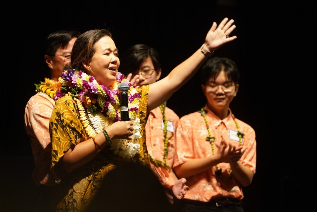Jill Tokuda gestures while speaking at the Hawaii convention center with her husband and sons.