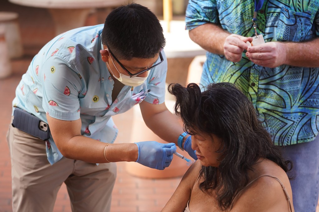 Psychiatrist Dr. Chad Koyanagi gives Cynthia an injection in Maunakea Marketplace. Dr. Koyanagi worked with IHS Outreach Navigation Coordinator David Warman and Shona Cobb to track down patients that needed medicine.