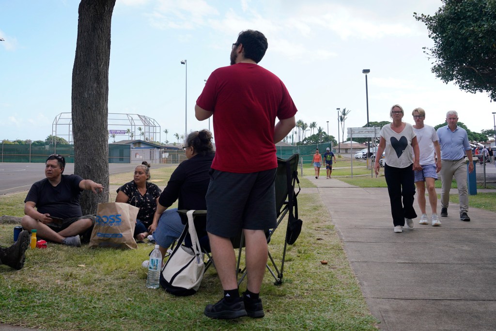 Alan Barrios, 53 of Lahaina, from left, and his family rest under a tree Wednesday, Aug. 9, 2023, at an emergency shelter at Maui High School in Kahului. Barrios’ apartment was completely destroyed by a fire which consumed the town of Lahaina. (Kevin Fujii/Civil Beat/2023)