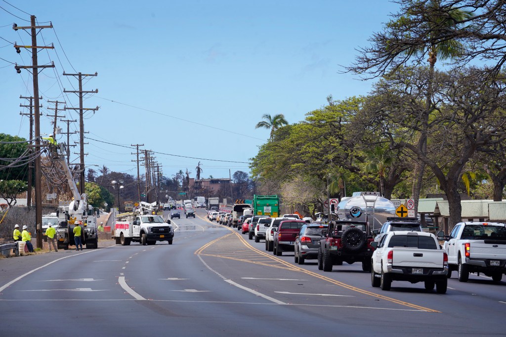 HECO crews work on utility lines as traffic builds to a standstill on Honoapiilani Highway as vehicles are turned onto the Lahaina Bypass Wednesday, Aug. 16, 2023, in Lahaina. A wildfire destroyed the historic town of Lahaina last week. (Kevin Fujii/Civil Beat/2023)
