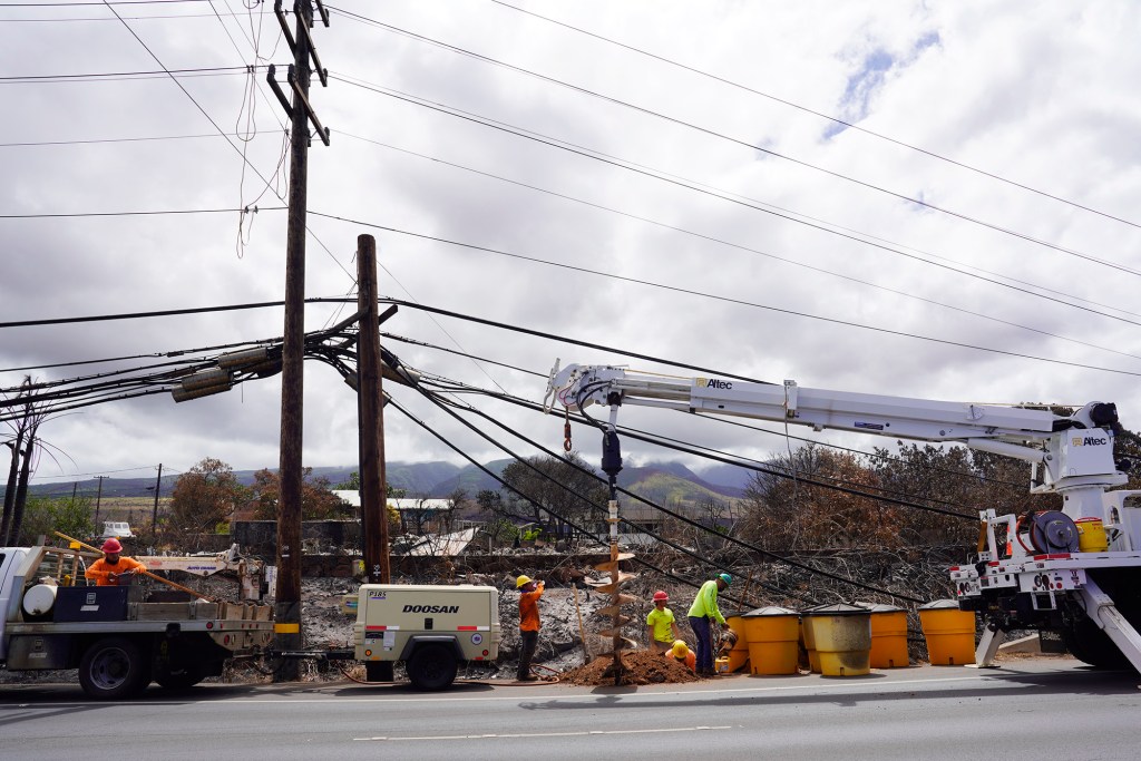 HECO crews install utility poles and lines on Honoapiilani Highway Wednesday, Aug. 16, 2023, in Lahaina. A wildfire destroyed the historic town of Lahaina last week. (Kevin Fujii/Civil Beat/2023)