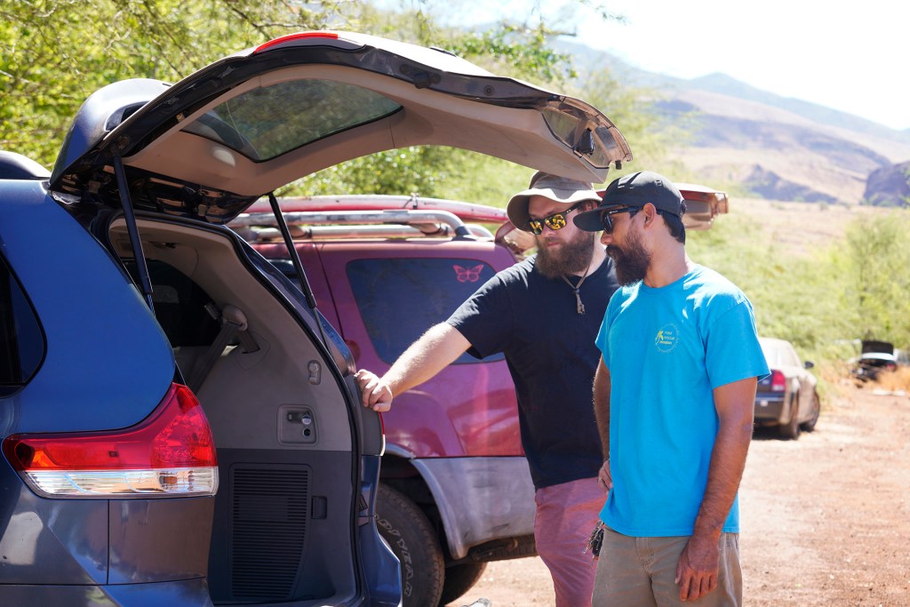 Maui Rescue Mission’s Ben Henrie, from left, and Sean Brown talk story with a man lying down in his van Tuesday, Aug. 22, 2023, near Lahaina. The pair are getting back on track to assist the unhoused after a wildfire destroyed the historic town of Lahaina. (Kevin Fujii/Civil Beat/2023)