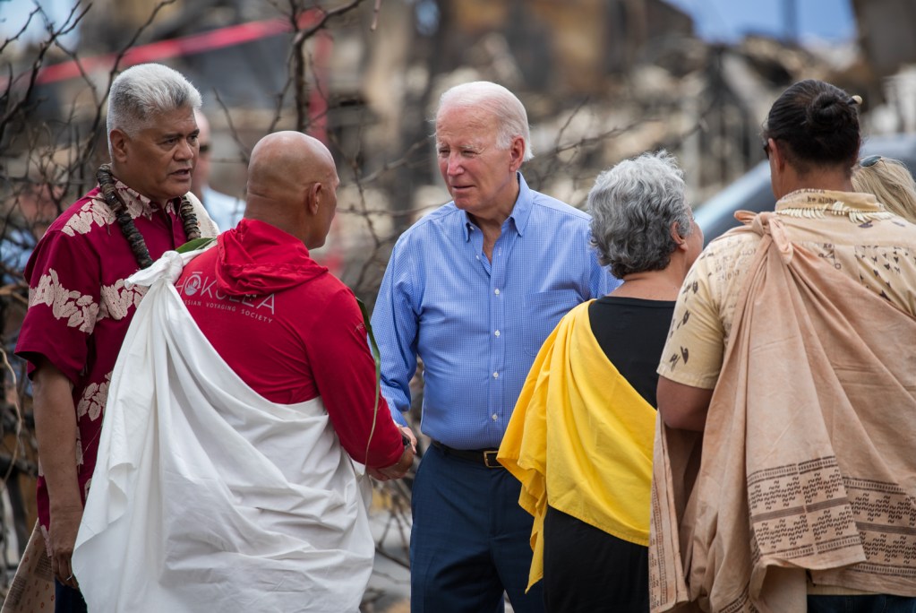 President Biden greets legendary waterman Archie Kalepa, center, with Kamana'opono Crabbe, left, former Office of Hawaiian Affairs chief executive, and other Hawaiian community leaders just off Front Street in Lahaina, Monday afternoon. (Nathan Eagle/Civil Beat/2023)