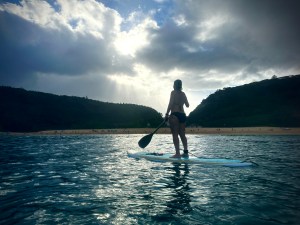 Natalie Borrello of Wahiawa paddles into Waimea Bay Sunday, Sept. 17, 2023, on the North Shore. Surf was flat and winds were light as rain clouds moved in with the Trade Winds. (Kevin Fujii/Civil Beat/2023)