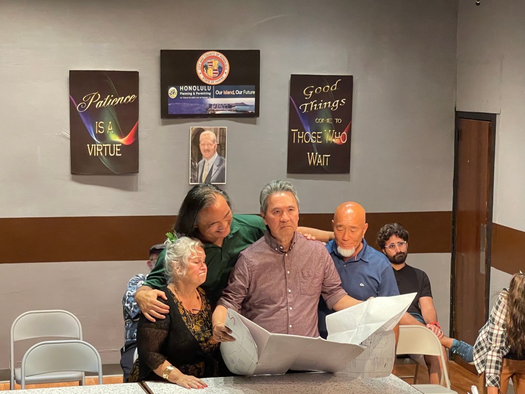 Eric Nemoto (center) played himself in the The Actors' Group production of Building Permit, a play based on the theater's real-life five-year journey of getting renovation plans approved by the Honolulu Department of Planning and Permitting. Nemoto is pictured in a fictional DPP waiting room with DPP applicants Gladys Mercante (played by Virginia Jones), Junior Hidalgo (played by Charles Kupahu Timtim), and Wes Zane (played by Eric Mita). (Christina Jedra/Civil Beat/2023)